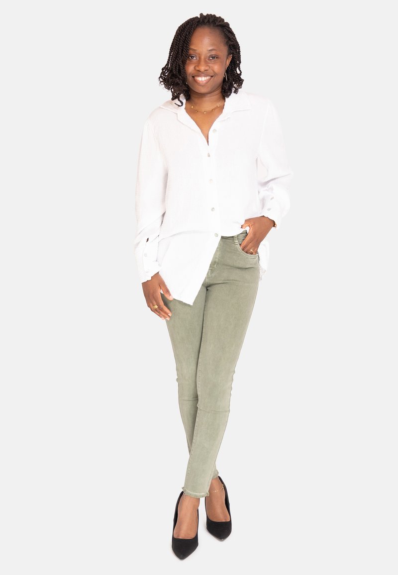 Hvid skjorte med knapper, lysegrønne skinny bukser, sorte hæle, struktureret stof, lagdelt design og slim fit skræddersyet til et moderne look.