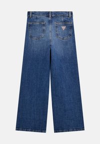 Keskmise sinise värvusega laia säärega teksased, millel on kõrge talje, viis taskut, peen tuhmumine ja väike kolmnurkne logoäpse tagaküljel.