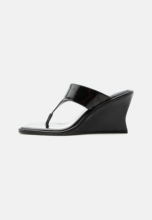Sandale compensée en cuir verni noir avec bride entre les orteils et bout carré, design moderne et épuré, vue de profil sur fond blanc.