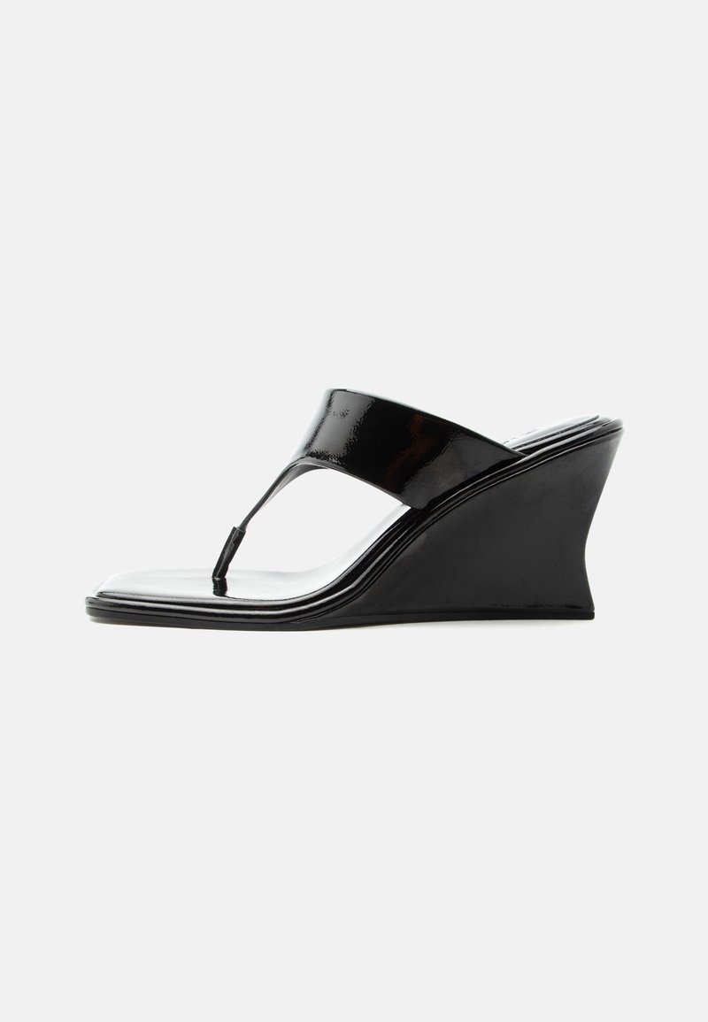 Sandale compensée en cuir verni noir avec bride entre les orteils et bout carré, design moderne et épuré, vue de profil sur fond blanc.