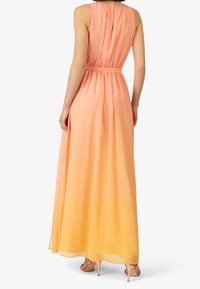 Maxi-jurk in vergradiënte tinten van perzik en oranje, gemaakt van lichtgewicht stof. Bevat een taillering en een vloeiende silhouet.
