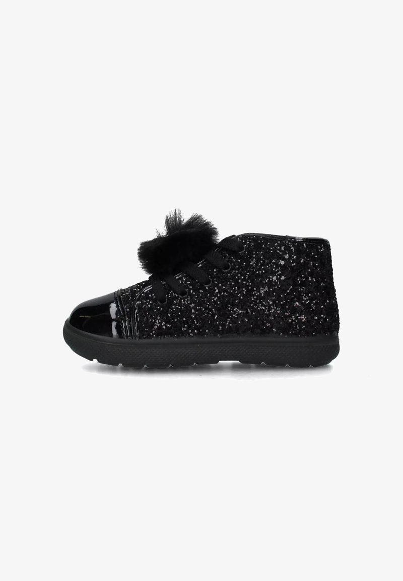 Sneaker alta nera glitterata con punta lucida, decorazione con pom-pom neri e lacci neri su uno sfondo bianco.