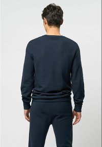 Navyblauwe sweatshirt met lange mouwen, geribde boorden en onderrand. Zachte, gestructureerde stof, aansluitend ontwerp en minimale naden. Draagt bijpassende pantalon.