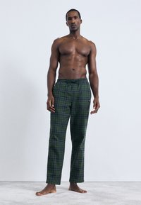 Zelené kárované pyžamové nohavice s elastickým pásom a šnúrkou, s jemnou textúrou a rovnými nohavicami. Žiadne viditeľné vrecká.