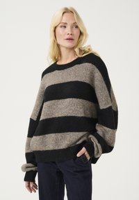 Maglione oversize con spesse strisce nere e marroni chiaro, realizzato in un morbido tessuto testurizzato con polsini e orlo a costine.