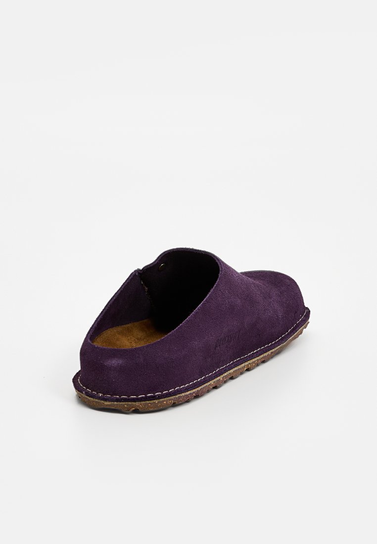 Lila Wildleder Slipper mit runder Zehenform, kontrastierendem Nähen und einer tanfarbenen Innensohle, entworfen für einfaches Tragen und Komfort.