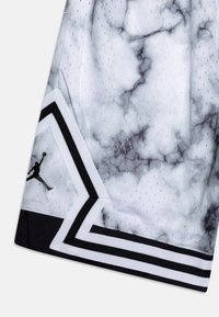 Pantalones cortos de baloncesto con un patrón de mármol blanco y gris, con ribetes en negro y blanco y un pequeño logo de Jumpman en negro cerca del dobladillo.