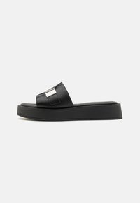 Sort slide sandal med en glat, blank finish og en bred rem. Har en metallisk detalje på remmen og en tyk platformssål.