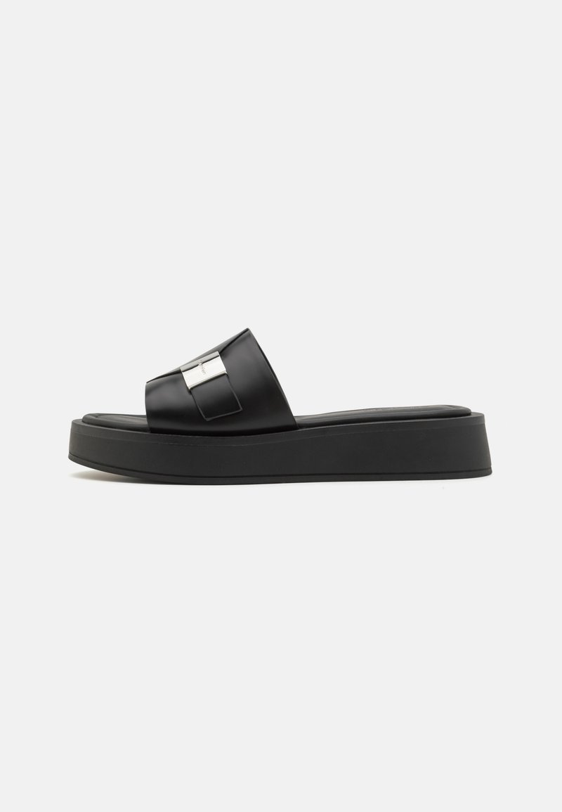 Sort slide sandal med en glat, blank finish og en bred rem. Har en metallisk detalje på remmen og en tyk platformssål.