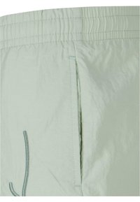 Lys grønne shorts laget av lettvektstoff, med elastisk midje, sidelomme og kontrasterende sømdetalj.