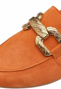 Oranje suède instapper met een gouden hardware accent in bladvorm, een gladde textuur en een ronde neus.