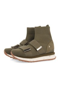 Zapatillas de punto verde olivo de caña alta con dos correas anchas y hebillas plateadas, suela media blanca y suela exterior de goma marrón texturizada.