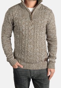 Kabelstrickpullover in Braun- und Cremetönen, mit einem Halbringkragen, gerippten Bündchen und einem strukturierten Muster überall.