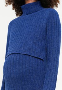 Blue ribbed knit sweater with a high neck and a cropped design, featuring a textured fabric and a relaxed fit suitable for maternity wear.