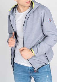 Grå zip-up jakke med hætte, der har en lys gul indvendig foring og lynlåsede lommer, lavet af et letvægtsmateriale.