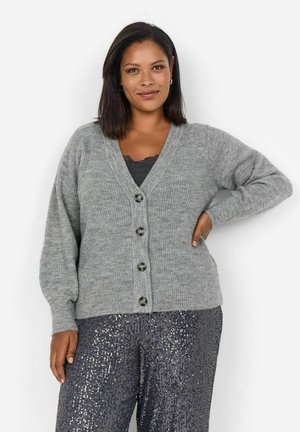 Šedý pletený kardigan s výstřihem do V, zapínáním na knoflíky a dlouhými rukávy, v kombinaci se sequined temnými kalhotami. Texturovaný detail látky.