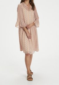 Robe à motif floral en rose doux, avec des rayures verticales, des manches évasées trois-quarts et une coupe décontractée avec une taille froncée.