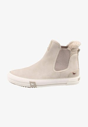 Botín beige tipo slip-on con suela de goma blanca, panel lateral elástico y forro peludo alrededor del tobillo, con un pequeño logo de caballo.