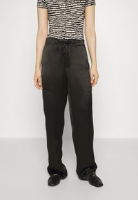 Breda svarta satinpants med dragsko i midjan, tillsammans med en kortärmad topp med ett zebramönster i beige och svart.