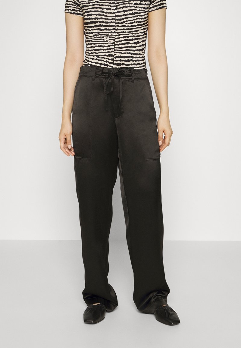 Breda svarta satinpants med dragsko i midjan, tillsammans med en kortärmad topp med ett zebramönster i beige och svart.