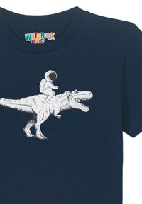 T-shirt en coton bleu marine présentant un graphique d'un astronaute chevauchant un T. rex, illustré en blanc avec des textures et des lignes détaillées.