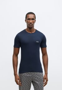 T-shirt blu navy a maniche corte con scollo rotondo e sottile logo "BOSS" sul petto, realizzata in tessuto liscio ed elastico.