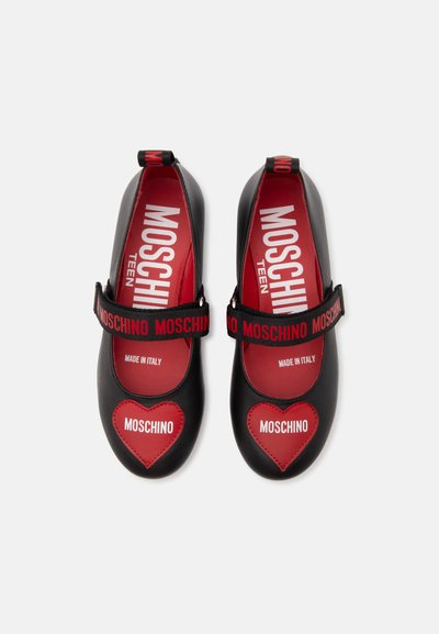 Chaussures Mary Jane noires avec des patchs en forme de cœur rouges étiquetés Moschino et des semelles intérieures rouges avec la marque Moschino Teen.
