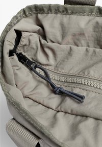 Interior de bolsa de tela gris que cuenta con un bolsillo con cremallera, textura suave y detalle con cordón en la apertura.