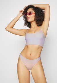 Conjunto de biquíni em duas peças em um suave tecido lilás em degradê. A parte de cima apresenta alças finas e um design cropped. A parte de baixo é elegante com uma cintura moderada.