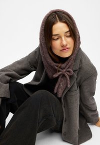 Gray wool blend blazer with large lapels, worn over a black top. Lavender knitted scarf tied at the front. Wide legged black pants.