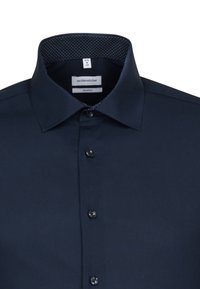 Donkerblauw overhemd met een gestructureerde kraag, subtiele stippenpatroon aan de binnenkant en zwarte knopen. Het materiaal lijkt glad en stijlvol.