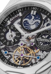 Zegarek automatyczny z stalową kopertą, czarną tarczą, srebrnymi wskazówkami godzin i minut, detalami zębatek, wyświetlaczem podwójnego czasu oraz logotypem marki.