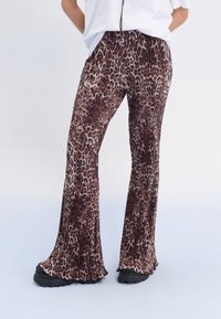 Pants med leopardmönster har hög midja, veckad design, vida ben och är gjorda av ett mjukt material, i kombination med svarta skor.