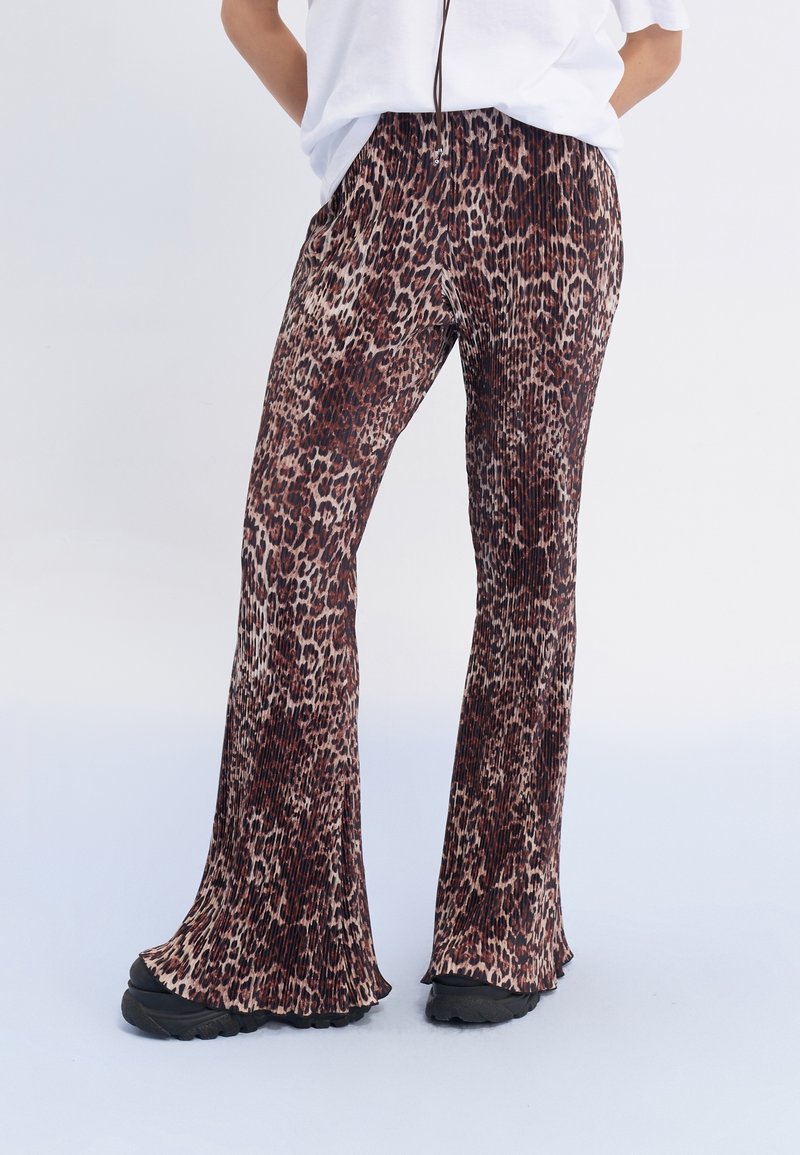 Pants med leopardmönster har hög midja, veckad design, vida ben och är gjorda av ett mjukt material, i kombination med svarta skor.