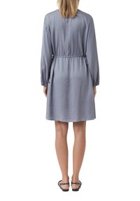 Jasnoszara sukienka uszyta z gładkiego materiału, z długimi rękawami, regulowanym paskiem w talii oraz swobodnym sylwetką w kształcie litery A.