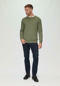 Zielony sweter dzianinowy z okrągłym dekoltem, w połączeniu z ciemnoniebieskimi spodniami typu slim fit i czarnymi trampkami. Casualowy styl z prążkowanymi mankietami i dołem.