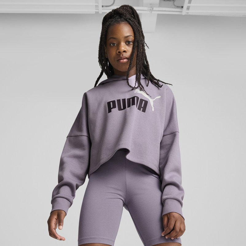 Sudadera recortada púrpura con logo "PUMA" y capucha, combinada con pantalones cortos de ciclista púrpuras a juego. Tejido suave y texturizado, corte relajado.