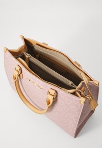 Ροζ τσάντα χειρός από ύφασμα με καφέ δερμάτινους χειρολαβές και λεπτομέρειες, διαθέτει πολλές θήκες και κλείσιμο με φερμουάρ. Επιφάνεια με υφή.