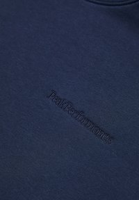 Maglietta sportiva blu navy realizzata in tessuto liscio; presenta il logo "PeakPerformance" in rilievo sul davanti, colletto rotondo e design aderente.