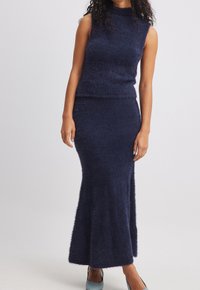 Completo blu navy a due pezzi realizzato in tessuto soffice; top senza maniche con colletto alto, e gonna lunga aderente con un leggero svaso all'orlo.