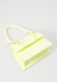 Punguță din piele patent galbenă cu mânere de sus, caracterizată printr-un sistem de închidere cu clapetă, accesorii din aur și detalii cusute. Design compact și structurat.