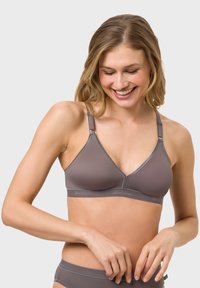 Grey wireless bralette with a triangular design, smooth fabric, adjustable straps, and logo detailing on the band.