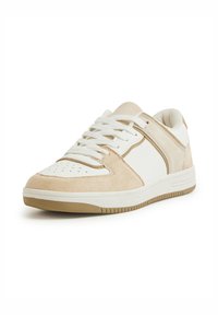 Sneaker bianco e beige con un davanti in suede, lati in pelle, punta perforata, lacci bianchi e suola in gomma con motivo antiscivolo.