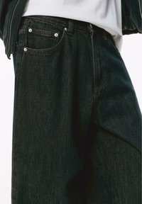 Jeans in denim scuro con vestibilità rilassata, cinque tasche e finiture in rivets argentati. Dettagli cuciti lungo le cuciture e la vita.