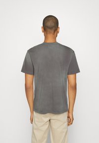 Gray short-sleeve t-shirt made of soft fabric with a crew neckline. Features a subtle texture and a curved hemline at the bottom.