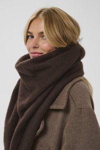 Ciemnobrązowy wełniany szal luźno ułożony wokół szyi, charakteryzujący się miękką fakturą i dużym, owiniętym designem, w połączeniu z beżowym płaszczem.