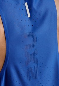 Niebieski sportowy tank top z oddychającą teksturą i subtelnymi perforacjami. Logo "2XU" w ciemniejszym odcieniu jest również widoczne na tkaninie.
