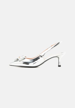 Chaussure à talon haut slingback métallisée argent avec bout pointu et nœud décoratif à l'avant, vue de profil sur fond blanc.