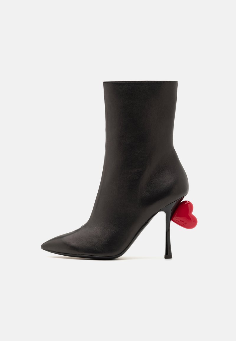 Black leather ankle boot with pointed toe, high heel, and red heart accent on heel. Smooth texture, sleek design, and modern silhouette.