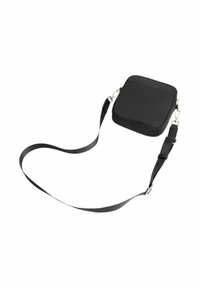 Fekete négyzet alakú crossbody táska sima anyagból, lapos elülső zsebbel, állítható pánttal és fémbetétes részletekkel rendelkezik.